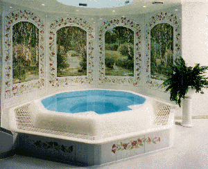 Whirlpool mit hochliegenderÜberlaufrinne. Dank der floral, verspielten Wandgestaltung und der harmonischen Verfliesung wirkt das großzügige Becken leicht und beschwingt.
