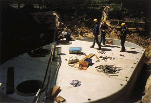Montage der verschraubbaren Beton-Fertigteile. Die links im Bild sichtbare Elektrohauptleitung mußte unterbaut werden. Während der Montage war rundwasserabsenkung erforderlich. Foto: MALLBETON
