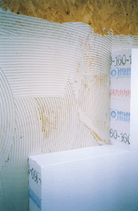 Bild 2: Anbringen des Wärmedämmverbundsystems. Hier werden 16 cm dicke Platten aus Polystyrol-Hartschaum mit Kunstharz Dispersionskleber auf die Spanplatten geklebt.