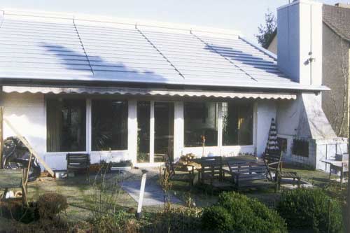 Bild 1: Gartenseite des renovierten Wohnhauses mit der Ansicht des neuen Daches in "vorbewittertem" Titanzink. Ausführungstechnische Einzelheiten, wie z.B. die Aufteilung der Dachfläche in vier Felder, die formschöne Randeinfassung und die Schornsteinbekleidung in Winkelstehfalztechnik, sind erkennbar.