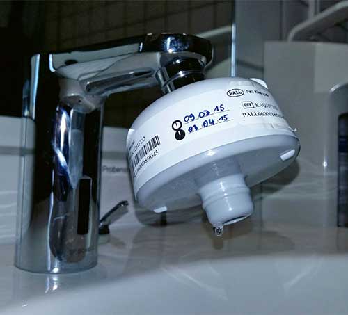 Bild 4: Zur unmittelbaren Gefahrenabwehr bei hohen mikrobiologischen Kontaminationen können auch im außermedizinischen Bereich temporär Sterilfilter eingesetzt werden, soweit sich der Filterabgang mindestens 20 mm über der Keramik befindet. Sanitärarmaturen mit bedarfsabhängiger Stagnationsspülung unterstützen den bestimmungsgemäßen Betrieb (im Bild: Waschtisch-Armatur Celis E).