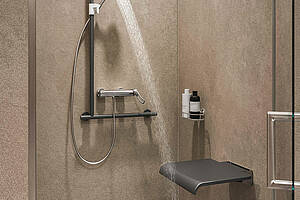 Für den barrierefreien Duschplatz wurden hier „F4LT-Med“- Thermostat-Wandbatterie, Handbrause und „Medcare“-Winkelgriff mit integriertem Handbrausehalter und Duschklappsitz in Basaltgrau kombiniert. Bild: KWC