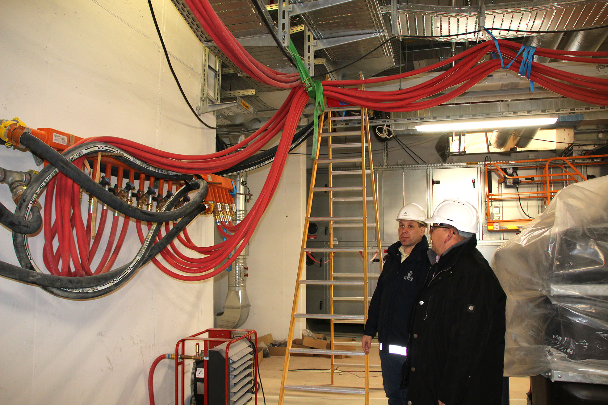 Alle Schläuche werden an der Decke aufgehängt. Dirk Sommer, zuständiger Planungsingenieur bei Vetter (r.) und mobiheat Key-Account-Manager Wolfgang Müller vor dem Verteiler der Heisswasserleitungen.